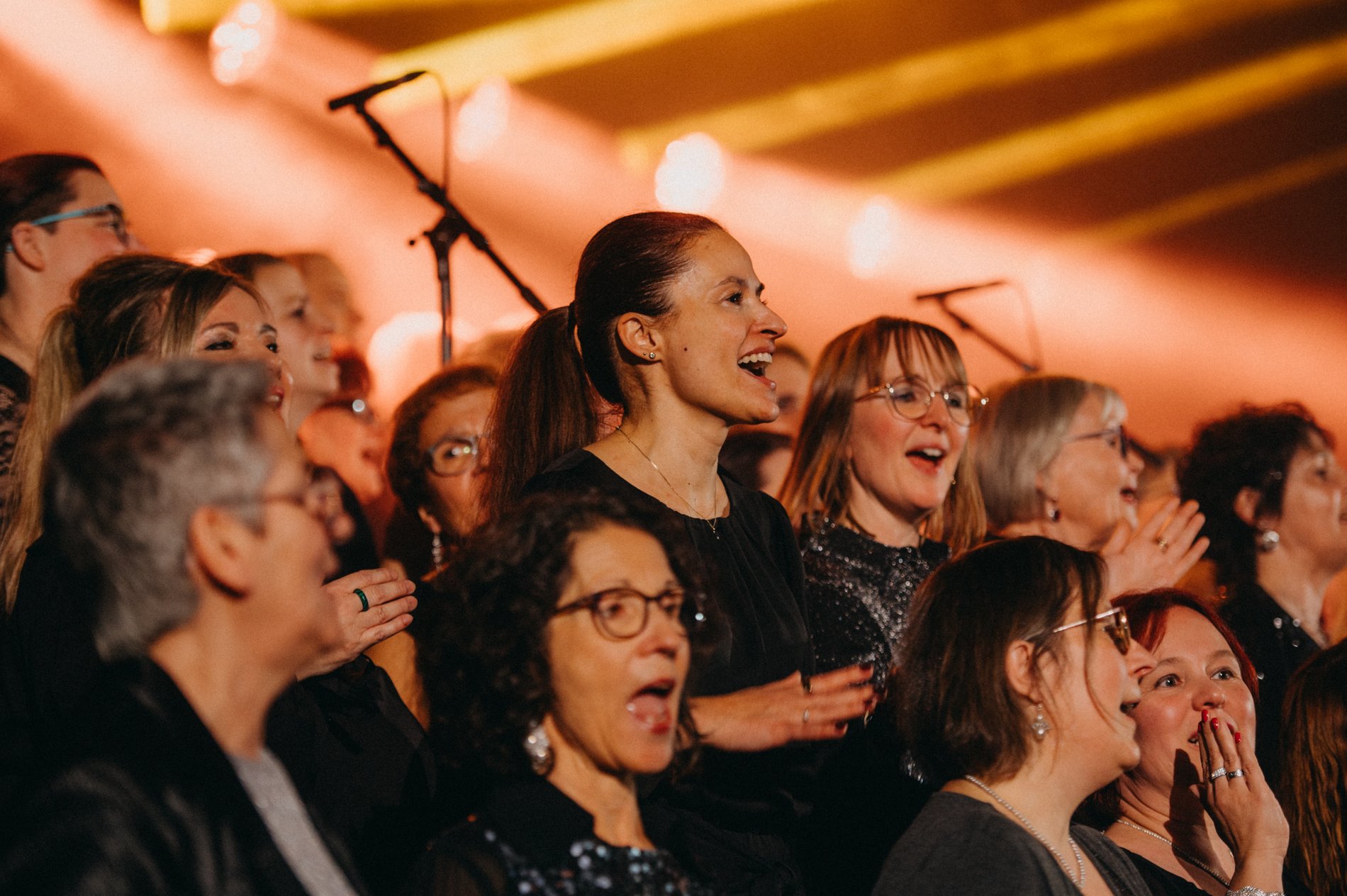 Sängerinnen und Sänger jeden Alters singen gemeinsam in warmem Licht